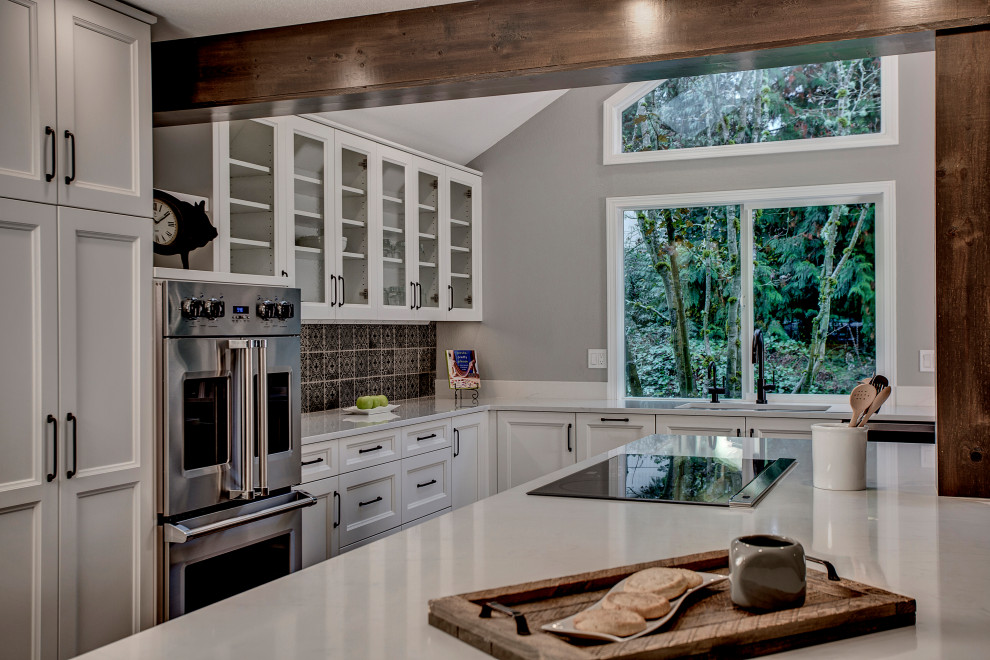 This is an example of a large transitional eat-in kitchen in Seattle with an undermount sink, recessed-panel cabinets, yellow cabinets, quartz benchtops, grey splashback, ceramic splashback, stainless steel appliances, medium hardwood floors, with island, brown floor and white benchtop.