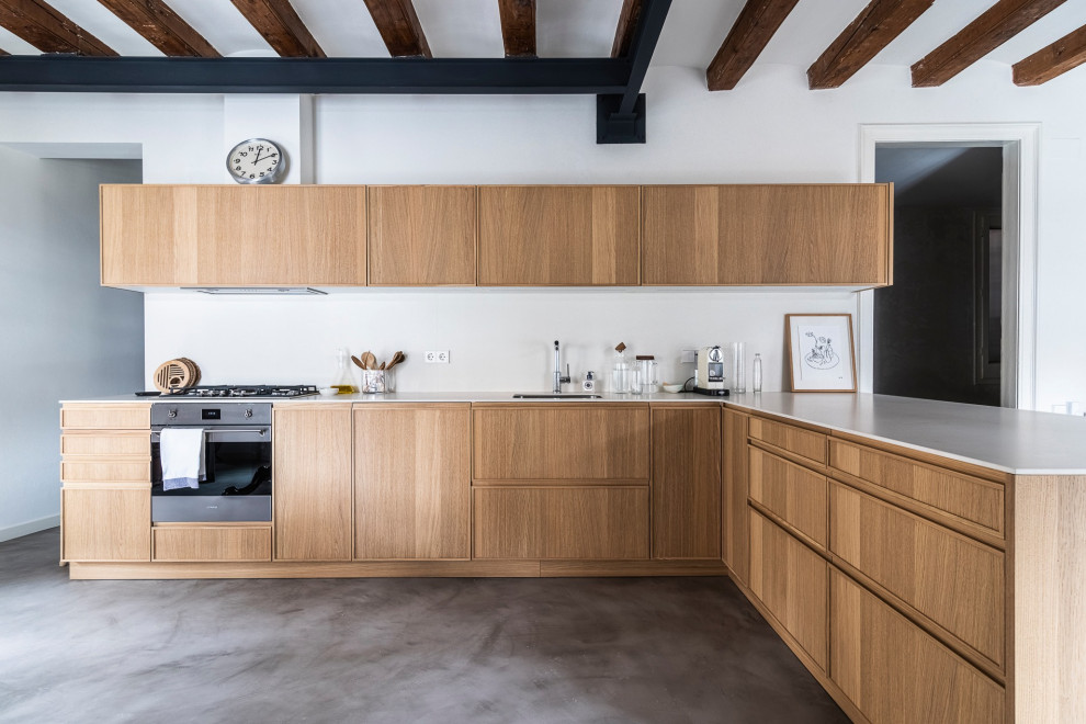 Inspiration for a large contemporary l-shaped open plan kitchen in Barcelona with an undermount sink, raised-panel cabinets, light wood cabinets, marble benchtops, white splashback, marble splashback, stainless steel appliances, concrete floors, a peninsula, grey floor, white benchtop and exposed beam.