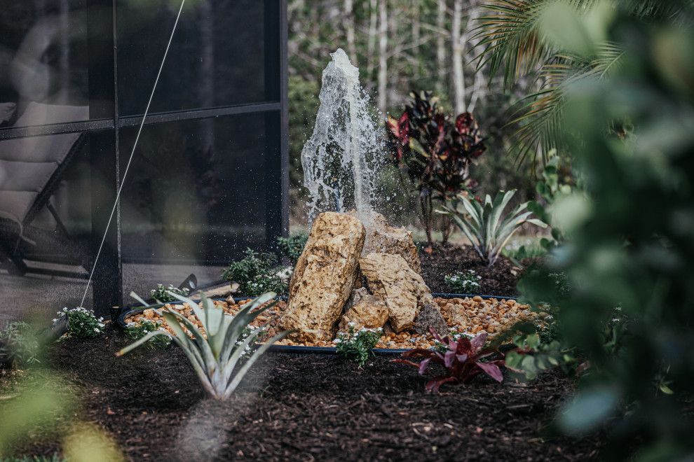 Photo of a medium sized world-inspired back formal partial sun garden in Other with a waterfall and mulch.