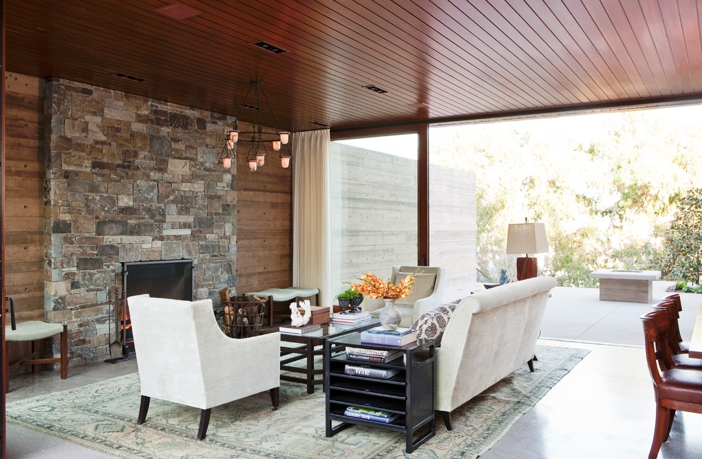 Photo of a contemporary living room in Los Angeles with concrete floors and a stone fireplace surround.