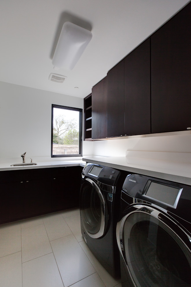 Design ideas for a large contemporary u-shaped dedicated laundry room in Houston with a drop-in sink, flat-panel cabinets, dark wood cabinets, white walls, a side-by-side washer and dryer, grey floor and white benchtop.