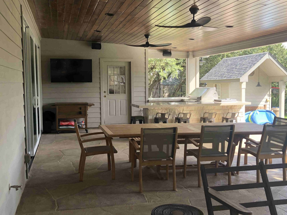 This is an example of an expansive eclectic backyard verandah in Austin with with fireplace.