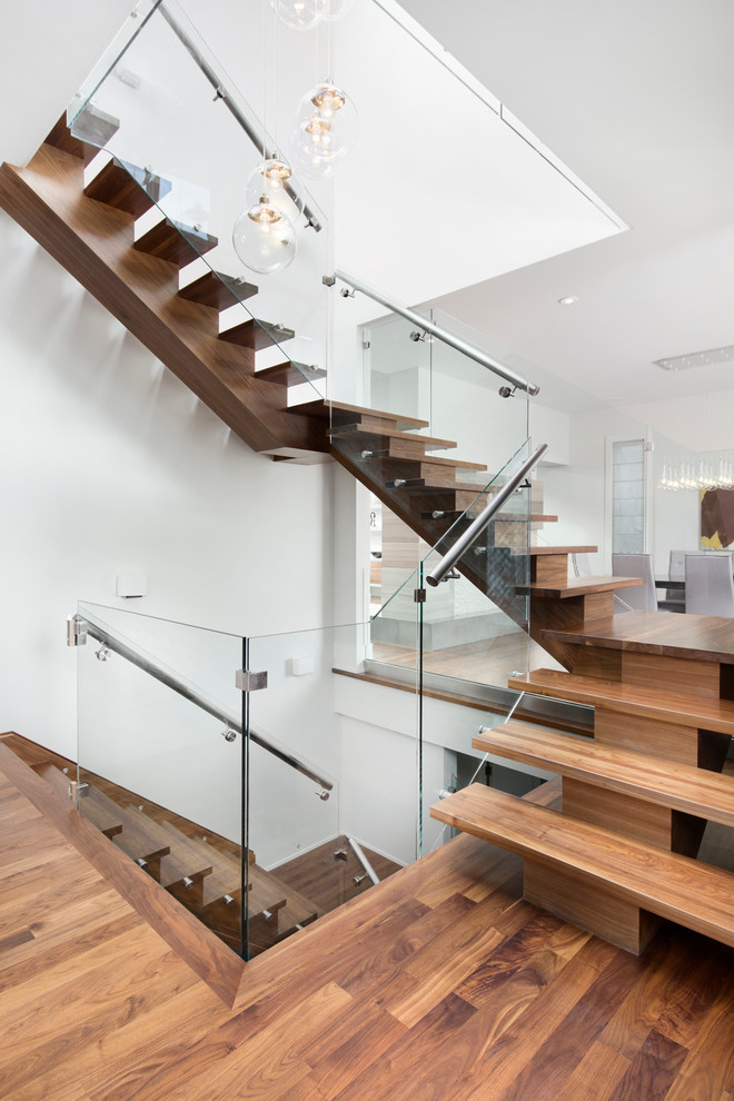 Design ideas for a contemporary wood u-shaped staircase in Calgary with open risers and glass railing.