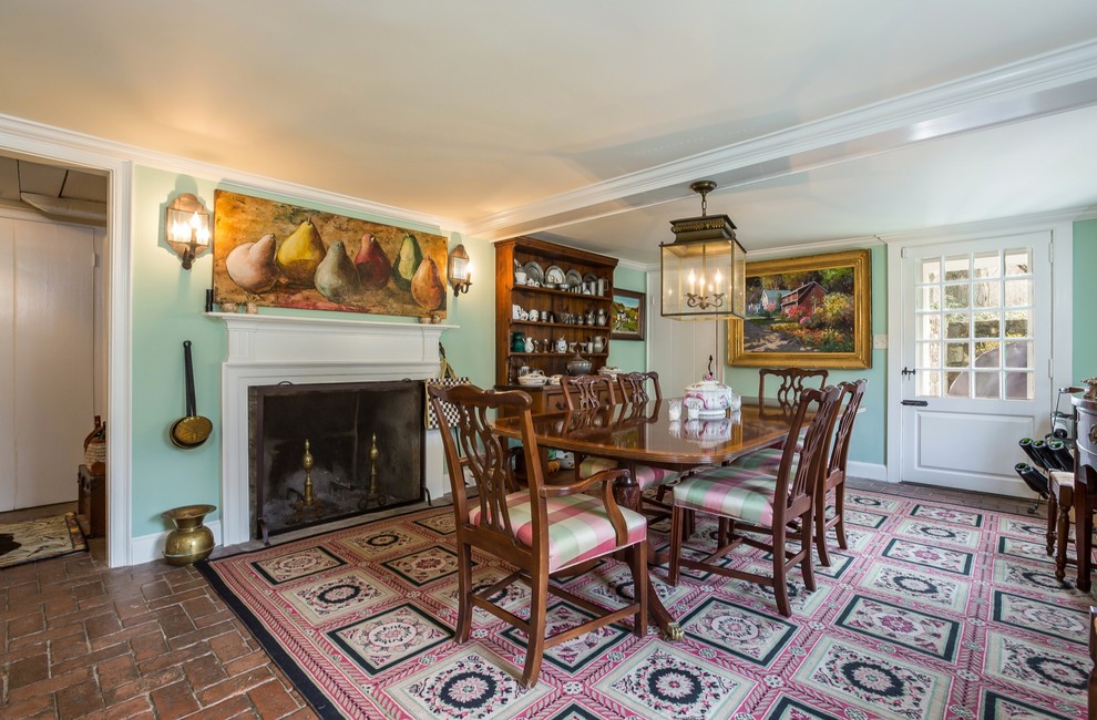 Photo of a large country separate dining room in New York with green walls, a standard fireplace, brown floor and brick floors.