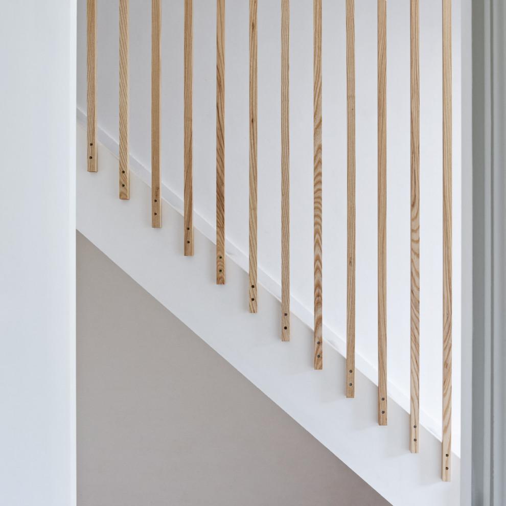 Cette image montre un petit escalier droit minimaliste avec des marches en moquette, des contremarches en moquette et un garde-corps en bois.