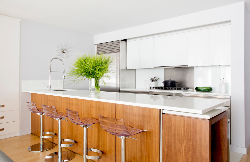 Inspiration for a contemporary kitchen in New York with an undermount sink, flat-panel cabinets, white cabinets, metallic splashback, stainless steel appliances and a peninsula.