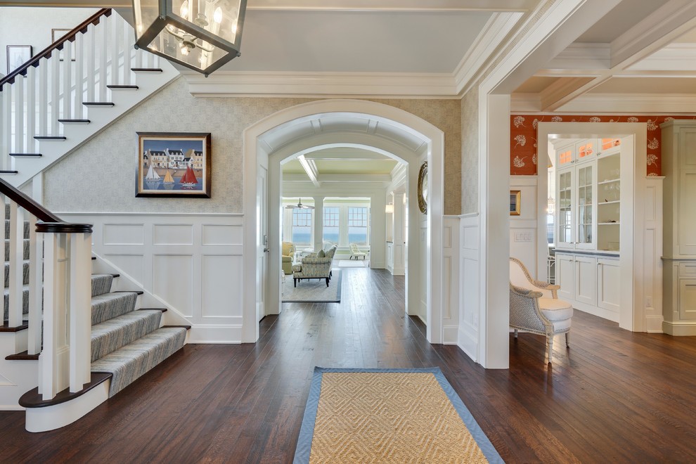 This is an example of an expansive beach style hallway in New York with multi-coloured walls, dark hardwood floors and brown floor.