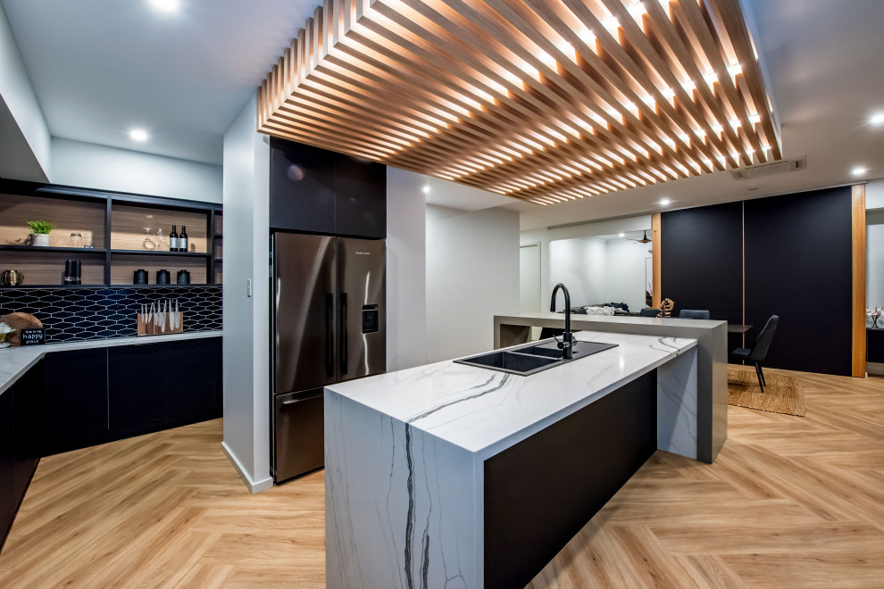 Contemporary l-shaped eat-in kitchen in Other with a double-bowl sink, flat-panel cabinets, black cabinets, black splashback, stainless steel appliances, light hardwood floors, with island, beige floor and multi-coloured benchtop.