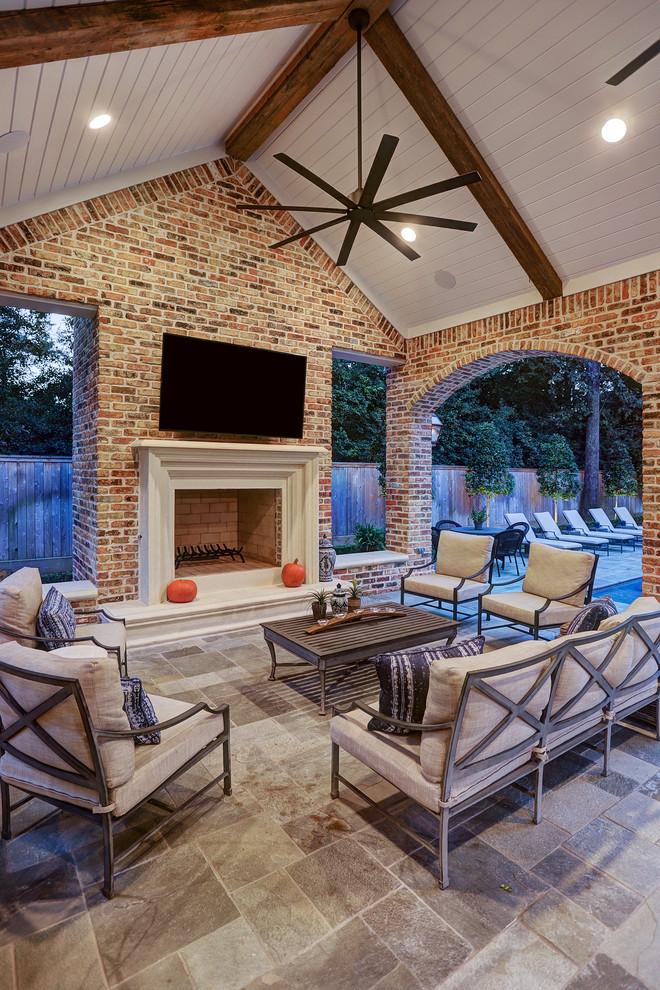 Design ideas for a mid-sized traditional backyard patio in Houston with an outdoor kitchen, natural stone pavers and a roof extension.
