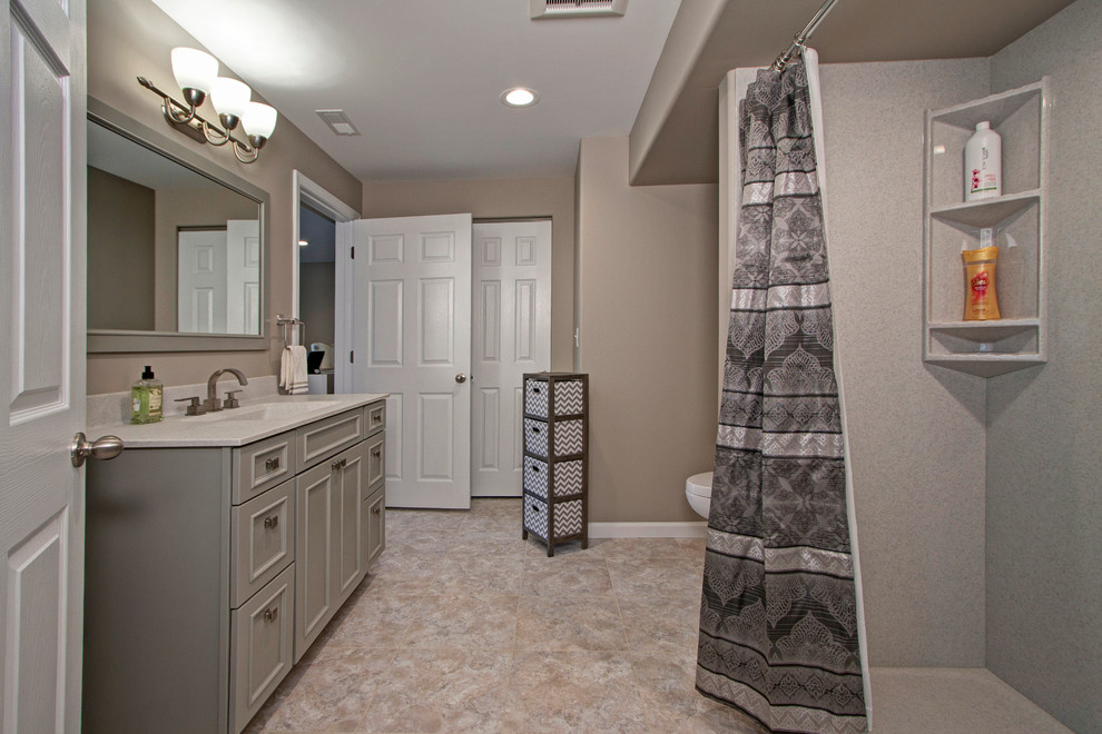 Photo of a large contemporary 3/4 bathroom in St Louis with recessed-panel cabinets, grey cabinets, a corner shower, a one-piece toilet, beige walls, vinyl floors, an integrated sink and onyx benchtops.