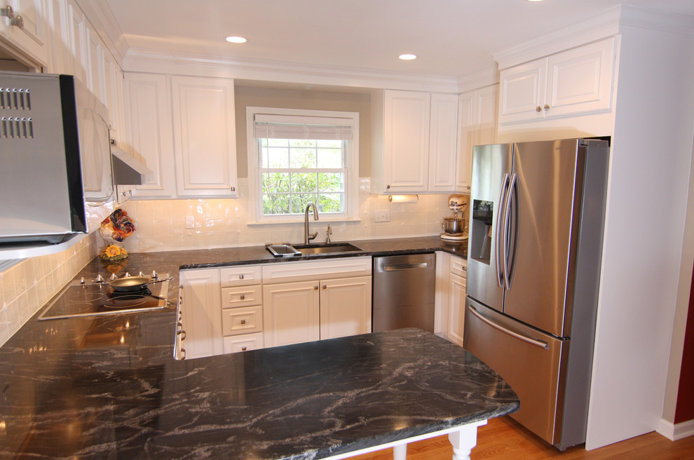 This is an example of a mid-sized traditional u-shaped eat-in kitchen in Philadelphia with an undermount sink, raised-panel cabinets, white cabinets, granite benchtops, white splashback, ceramic splashback, stainless steel appliances, light hardwood floors and a peninsula.