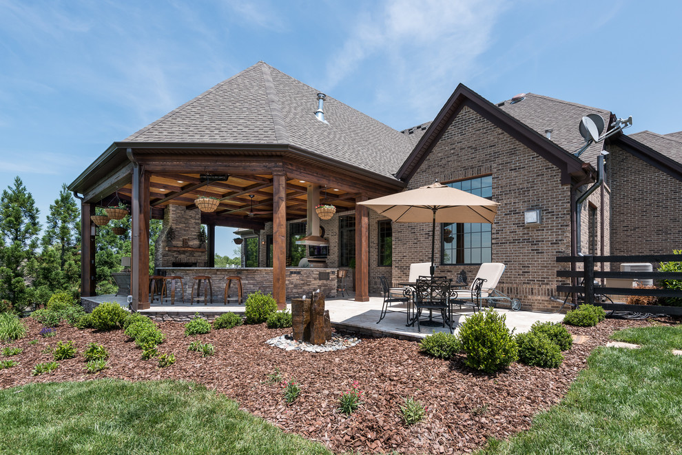 Patio kitchen - rustic backyard stone patio kitchen idea with a roof extension