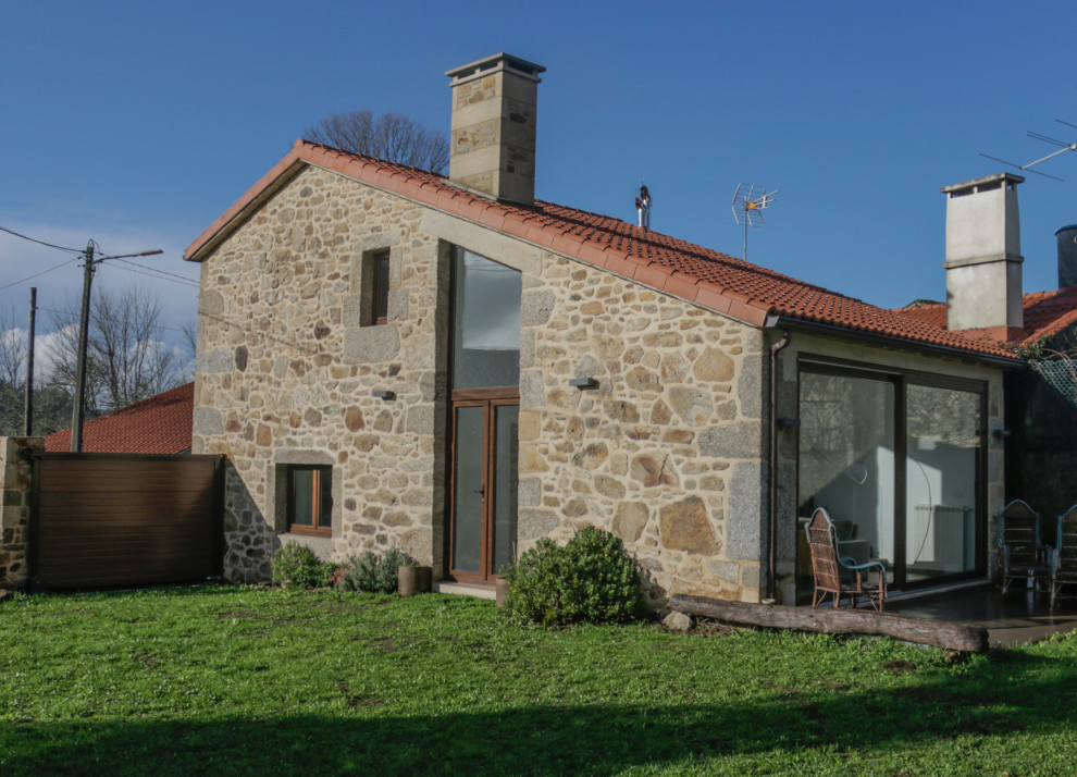 Imagen de fachada de casa marrón rústica grande de dos plantas con revestimiento de piedra, tejado a dos aguas, tejado de teja de barro y teja