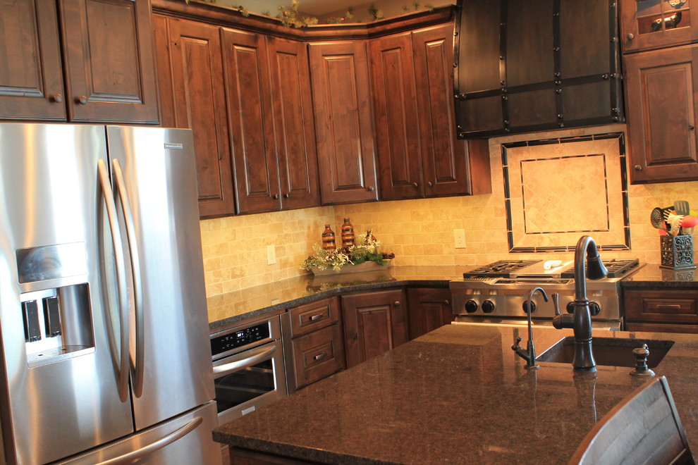 Example of a mid-sized mountain style u-shaped medium tone wood floor open concept kitchen design with raised-panel cabinets, dark wood cabinets, granite countertops, beige backsplash, ceramic backsplash, black appliances and an island