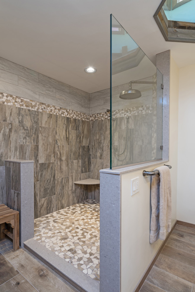Photo of a large country master bathroom in Philadelphia with raised-panel cabinets, distressed cabinets, a curbless shower, a two-piece toilet, gray tile, porcelain tile, beige walls, porcelain floors, engineered quartz benchtops, brown floor, an open shower and beige benchtops.