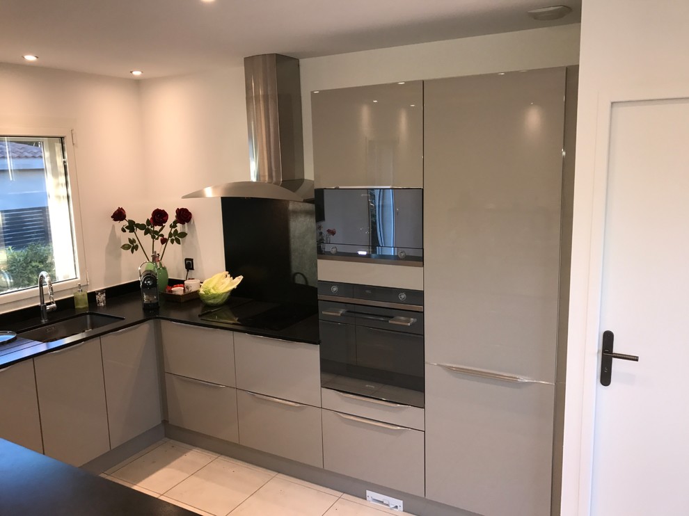 Idée de décoration pour cuisine américaine en U avec un évier intégré, un placard à porte affleurante, des portes de placard grises, un plan de travail en granite, une crédence noire, un sol en carrelage de céramique, îlot, un sol beige et plan de travail noir.