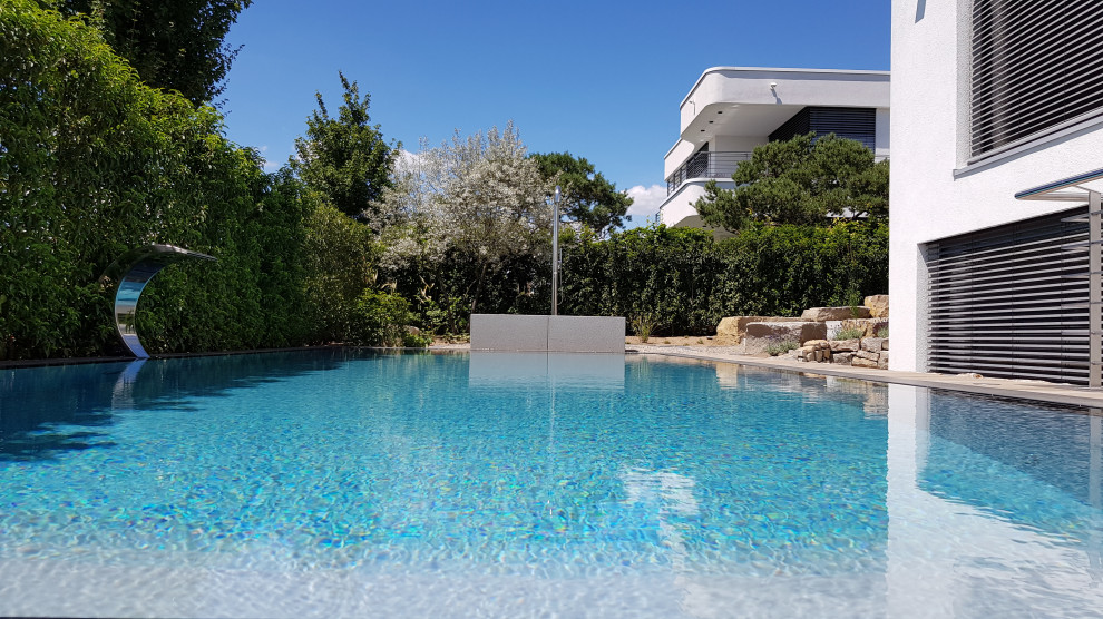 Großer Mediterraner Infinity-Pool neben dem Haus in rechteckiger Form mit Natursteinplatten in Frankfurt am Main