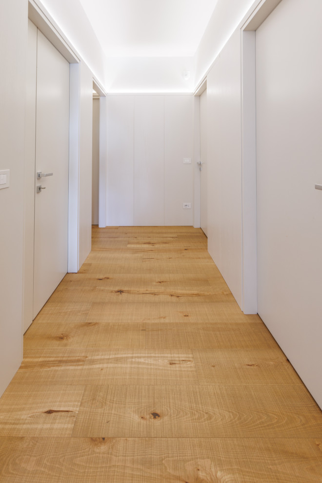 Immagine di un ingresso o corridoio minimal di medie dimensioni con pareti bianche, pavimento in legno verniciato e pannellatura
