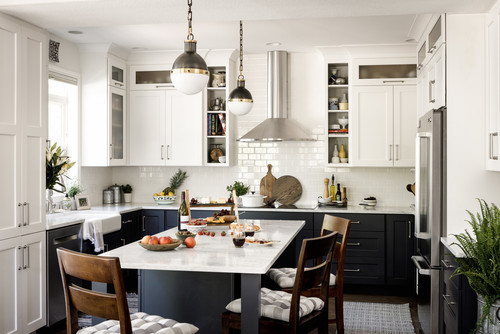 Two-tone kitchen with white upper cabinets, navy blue lower cabinets, marble island, and brass-accent pendant lights — stylish contrast for modern homes