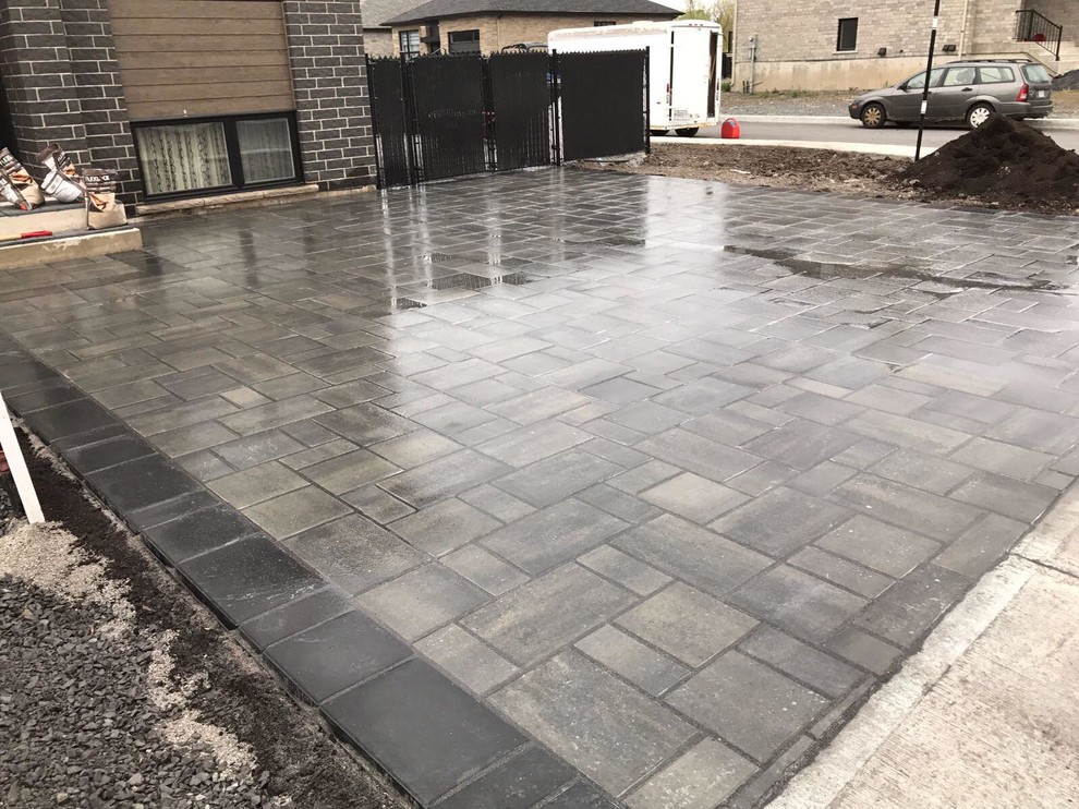 This is an example of a small modern front yard full sun driveway for summer in Montreal with with outdoor playset and concrete pavers.