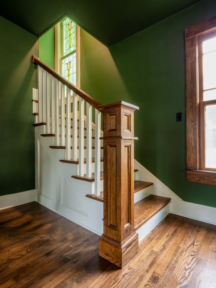 Cette image montre un grand escalier peint craftsman en L avec des marches en bois et un garde-corps en bois.