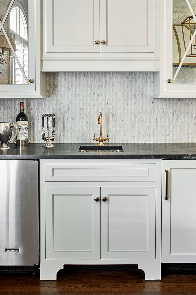 Design ideas for a mid-sized traditional single-wall wet bar in Charlotte with an undermount sink, beaded inset cabinets, white cabinets, marble benchtops, grey splashback, stone tile splashback and medium hardwood floors.