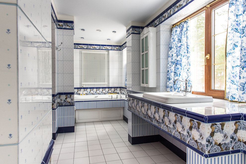 Design ideas for a country master bathroom in Saint Petersburg with a drop-in tub, white tile, blue tile, ceramic tile, a drop-in sink, tile benchtops and white floor.