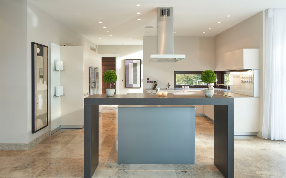 This is an example of a large contemporary u-shaped kitchen in Dublin with an undermount sink, flat-panel cabinets, white cabinets, mirror splashback, stainless steel appliances, with island, grey floor and grey benchtop.