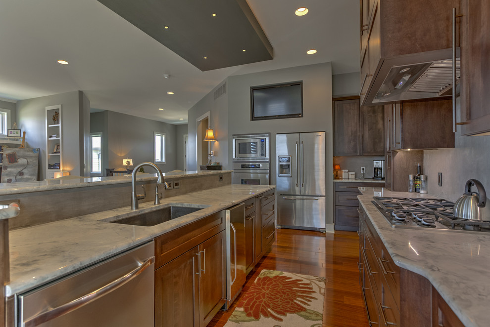 Inspiration for a medium tone wood floor eat-in kitchen remodel with dark wood cabinets, granite countertops, gray backsplash, stainless steel appliances and an island
