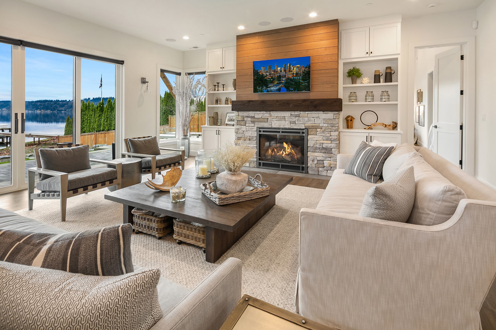 This is an example of a beach style family room in Seattle with white walls, a standard fireplace, a stone fireplace surround and a wall-mounted tv.
