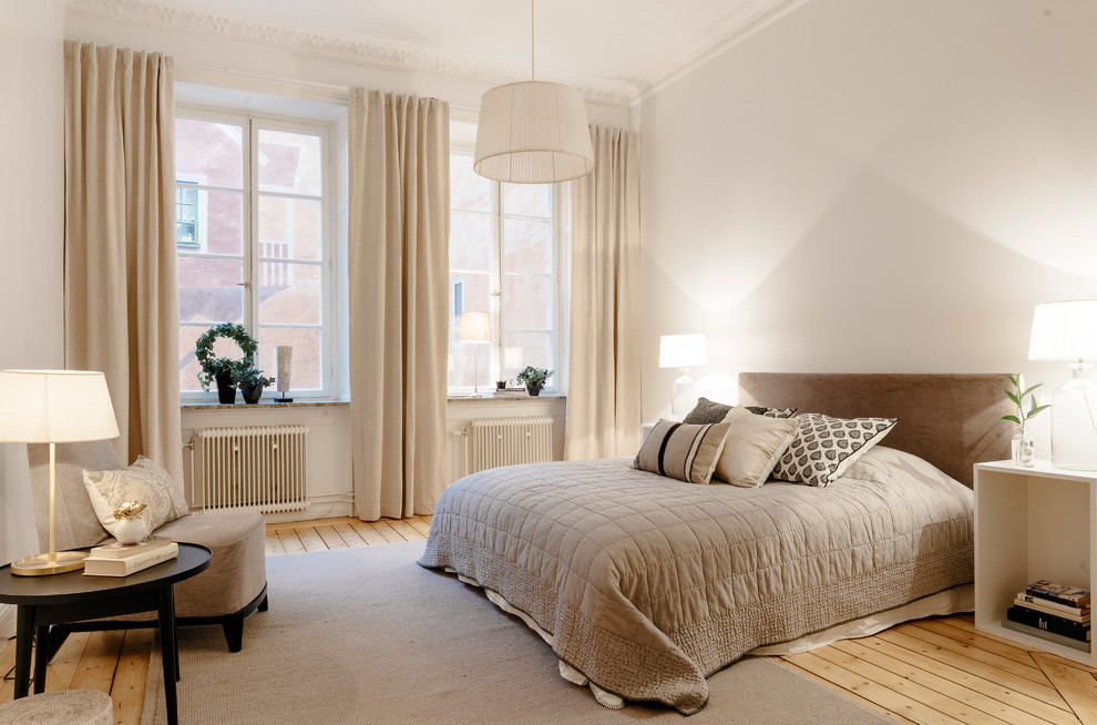 Design ideas for a mid-sized traditional master bedroom in Stockholm with white walls, light hardwood floors and no fireplace.