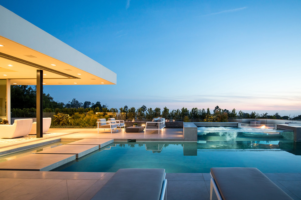 Inspiration for an expansive contemporary backyard custom-shaped lap pool in Los Angeles with a hot tub and tile.