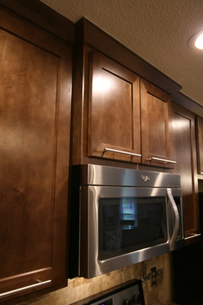 Eat-in kitchen - mid-sized transitional l-shaped porcelain tile eat-in kitchen idea in Jacksonville with an undermount sink, shaker cabinets, brown cabinets, granite countertops, beige backsplash, stone tile backsplash, stainless steel appliances and a peninsula