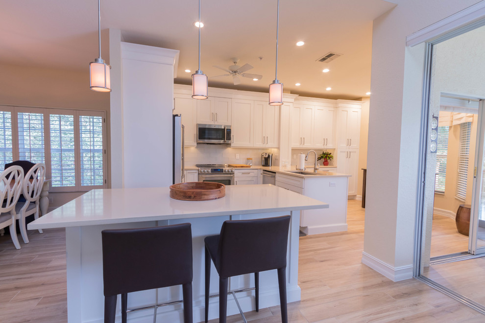 Design ideas for a large transitional single-wall eat-in kitchen in Miami with a single-bowl sink, shaker cabinets, white cabinets, quartz benchtops, white splashback, glass tile splashback, stainless steel appliances, ceramic floors and with island.