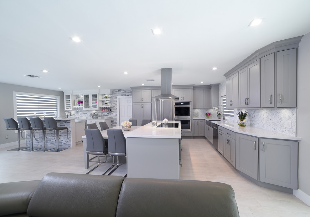 Open concept kitchen - large transitional l-shaped porcelain tile and gray floor open concept kitchen idea in Miami with a farmhouse sink, shaker cabinets, gray cabinets, quartz countertops, gray backsplash, marble backsplash, stainless steel appliances and two islands