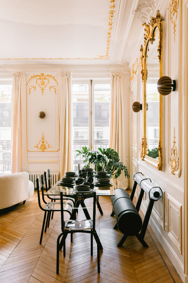 Immagine di una grande sala da pranzo aperta verso il soggiorno classica con pareti bianche, parquet chiaro e boiserie