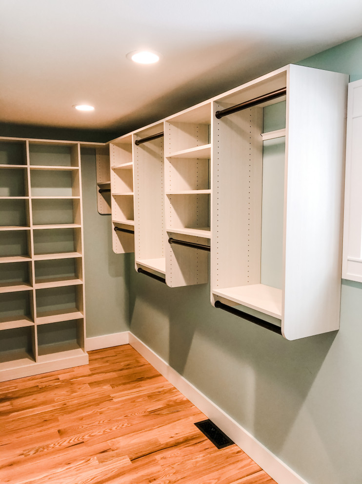 Mid-sized arts and crafts gender-neutral walk-in wardrobe in Grand Rapids with open cabinets, light wood cabinets, light hardwood floors and orange floor.