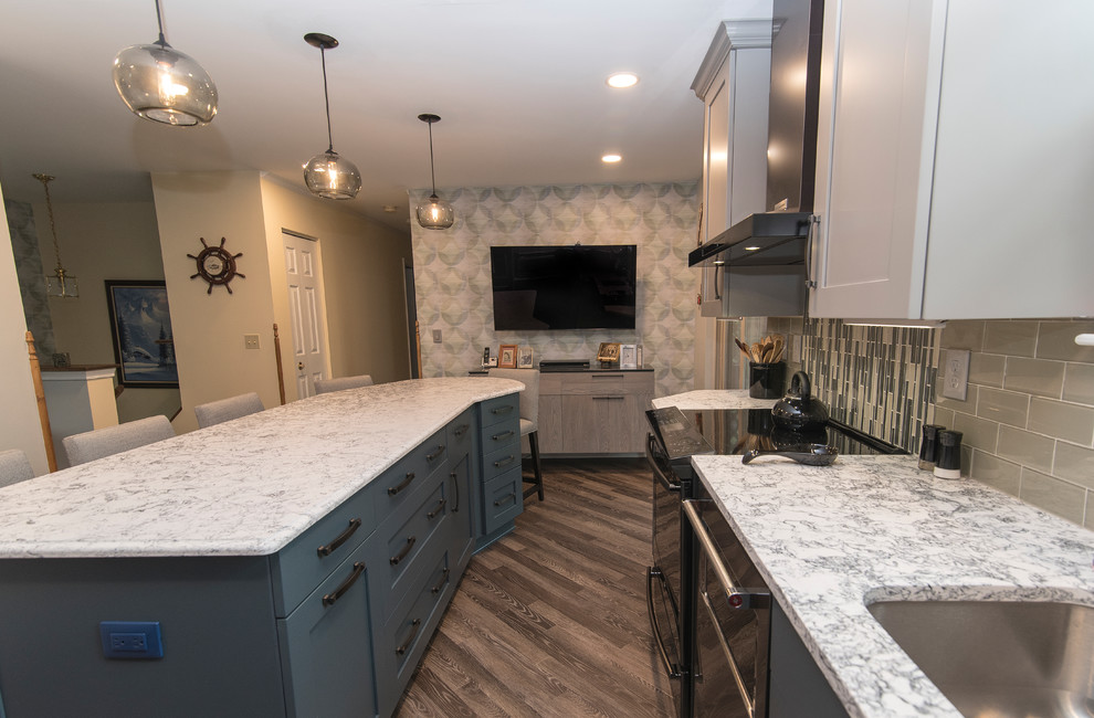 Example of a mid-sized transitional l-shaped brown floor eat-in kitchen design in Baltimore with a single-bowl sink, shaker cabinets, gray cabinets, quartz countertops, gray backsplash, subway tile backsplash, stainless steel appliances, an island and white countertops