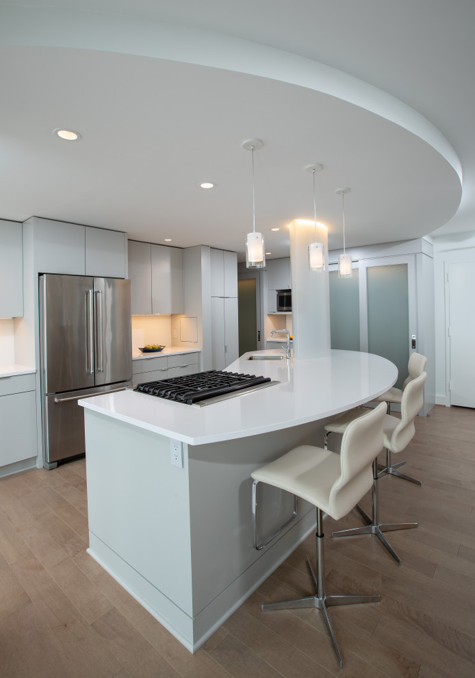 This is an example of a contemporary eat-in kitchen in DC Metro with an undermount sink, flat-panel cabinets, grey cabinets, quartz benchtops, stainless steel appliances, medium hardwood floors, with island, beige floor and white benchtop.