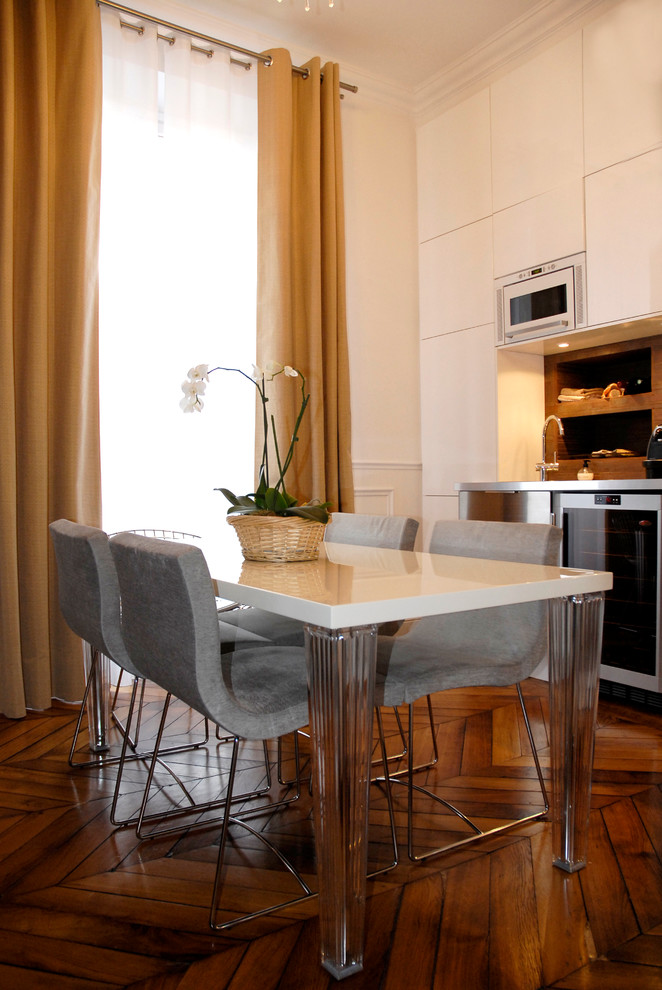 Mid-sized contemporary kitchen/dining combo in Paris with white walls and medium hardwood floors.