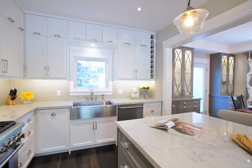 Inspiration for a large transitional l-shaped dark wood floor and brown floor eat-in kitchen remodel in Toronto with a farmhouse sink, shaker cabinets, white cabinets, quartz countertops, gray backsplash, subway tile backsplash, stainless steel appliances, an island and gray countertops