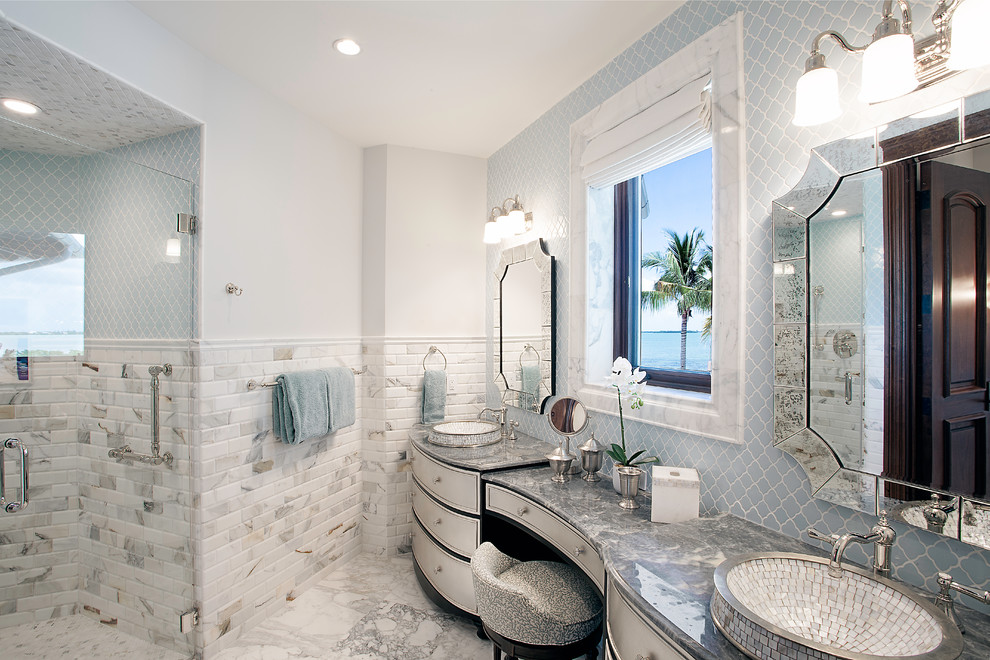 Photo of a large tropical master bathroom in Miami with white cabinets, white walls, a curbless shower, gray tile, subway tile, a drop-in sink, grey floor, a hinged shower door, recessed-panel cabinets and granite benchtops.
