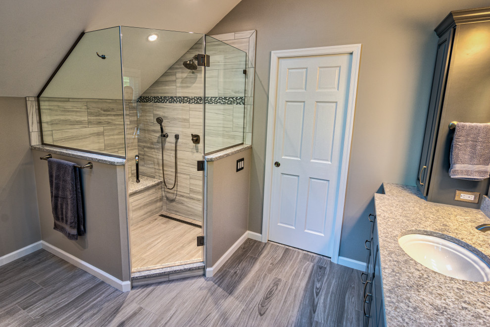 Photo of a large traditional master bathroom in Philadelphia with raised-panel cabinets, grey cabinets, a corner shower, a two-piece toilet, gray tile, porcelain tile, grey walls, porcelain floors, an undermount sink, engineered quartz benchtops, grey floor, a hinged shower door, white benchtops, a shower seat, a double vanity, a built-in vanity and vaulted.