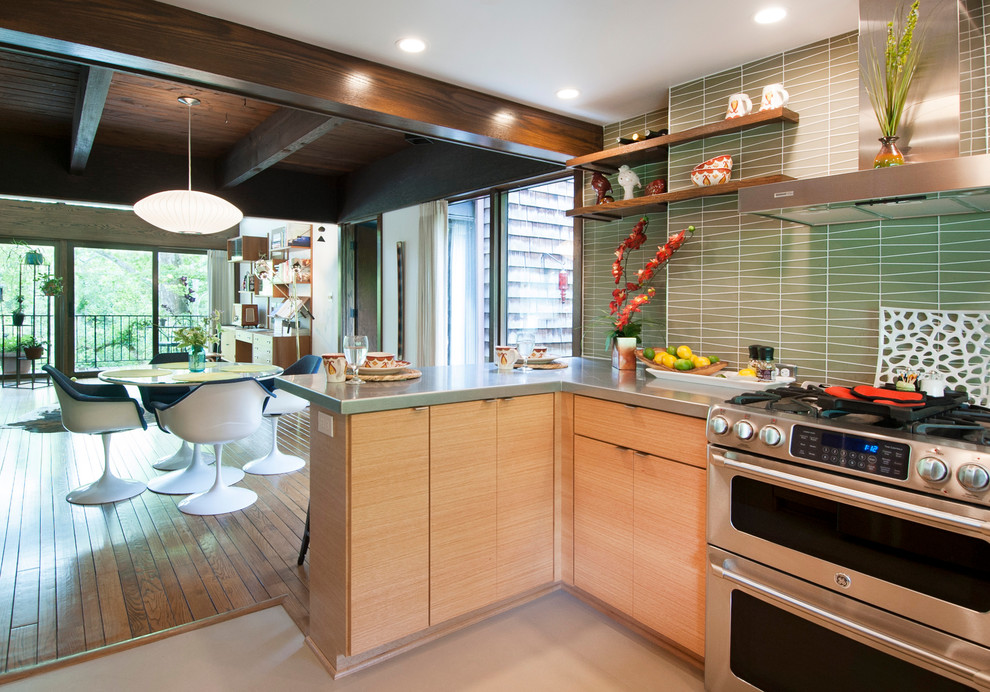 Design ideas for a small midcentury u-shaped open plan kitchen in Columbus with an integrated sink, flat-panel cabinets, light wood cabinets, stainless steel benchtops, green splashback, glass tile splashback, stainless steel appliances, linoleum floors and a peninsula.