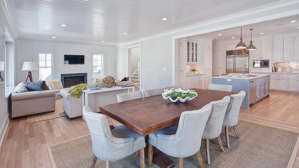 This is an example of a large beach style open concept family room in Other with white walls, light hardwood floors, a standard fireplace, a stone fireplace surround, a wall-mounted tv and brown floor.