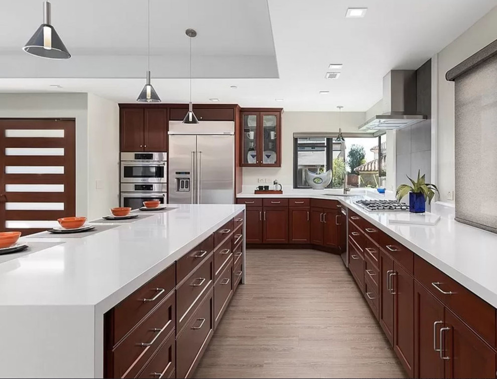 Mid-sized contemporary galley open plan kitchen in Orange County with a triple-bowl sink, raised-panel cabinets, white cabinets, quartzite benchtops, white splashback, porcelain splashback, stainless steel appliances, vinyl floors, with island, beige floor, white benchtop and coffered.