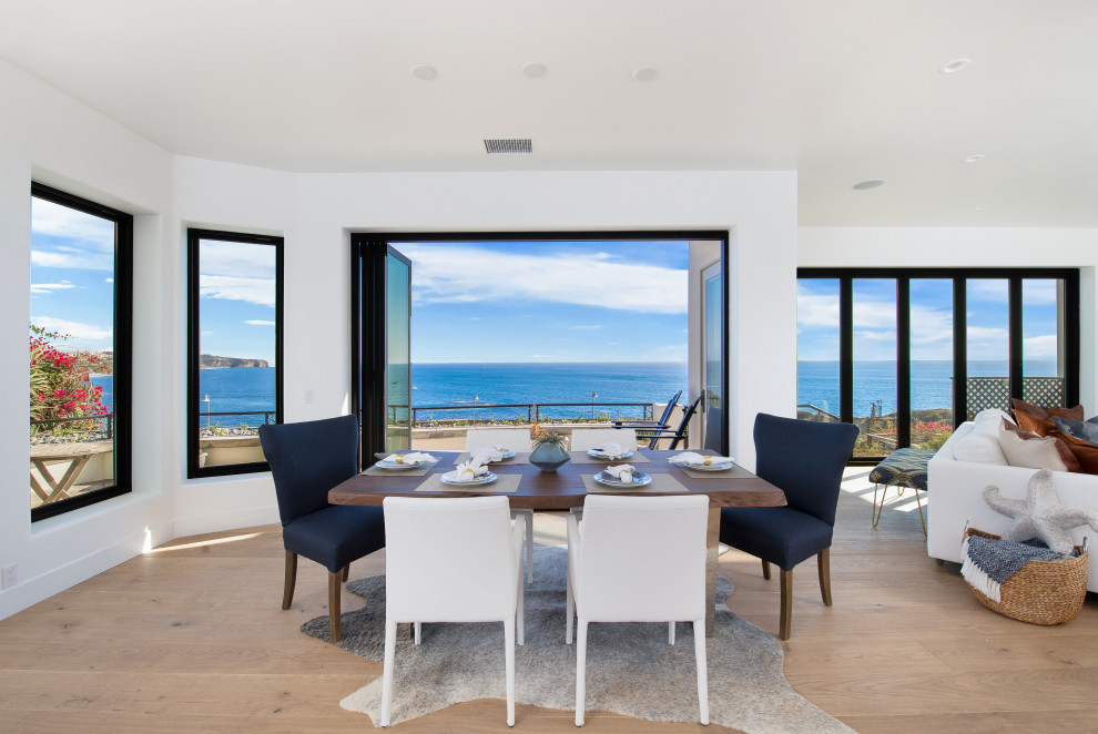 Photo of an expansive beach style open plan dining in Orange County with white walls, medium hardwood floors, a corner fireplace, a tile fireplace surround, brown floor, wood and wood walls.