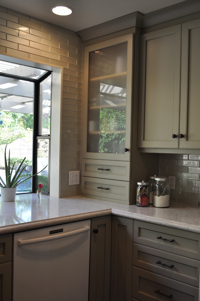 Photo of a mid-sized traditional l-shaped separate kitchen in Sacramento with an undermount sink, shaker cabinets, beige cabinets, solid surface benchtops, beige splashback, ceramic splashback, white appliances, porcelain floors and a peninsula.