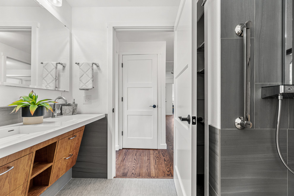 Photo of a small contemporary 3/4 bathroom in Seattle with flat-panel cabinets, light wood cabinets, a curbless shower, a bidet, gray tile, porcelain tile, white walls, porcelain floors, an integrated sink, solid surface benchtops, grey floor, a shower curtain, white benchtops, a shower seat, a double vanity and a floating vanity.