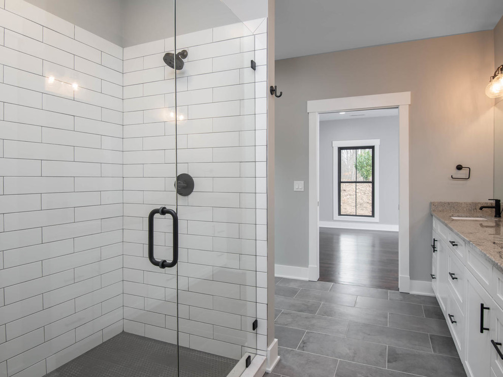 Design ideas for a large country master bathroom in Other with shaker cabinets, white cabinets, an alcove shower, a one-piece toilet, white tile, subway tile, grey walls, porcelain floors, an undermount sink, granite benchtops, grey floor, a hinged shower door and grey benchtops.